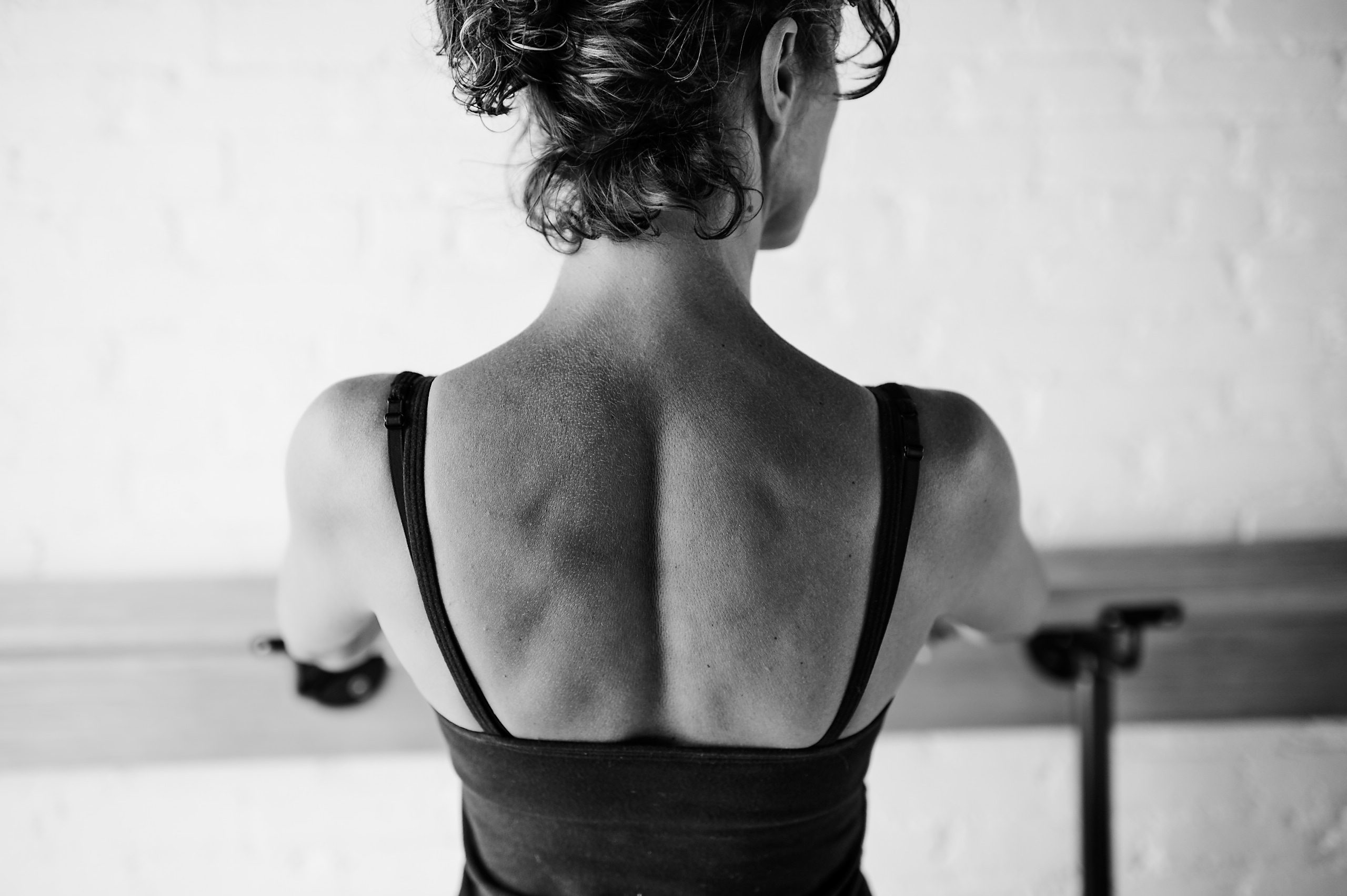 Black and white image of woman's back on a bar method studio