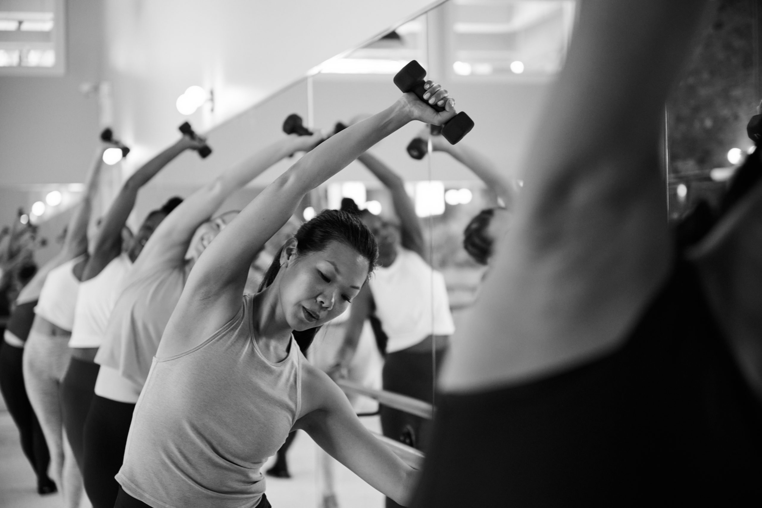 Woman working out with weights at the barre in Bar Method Studio