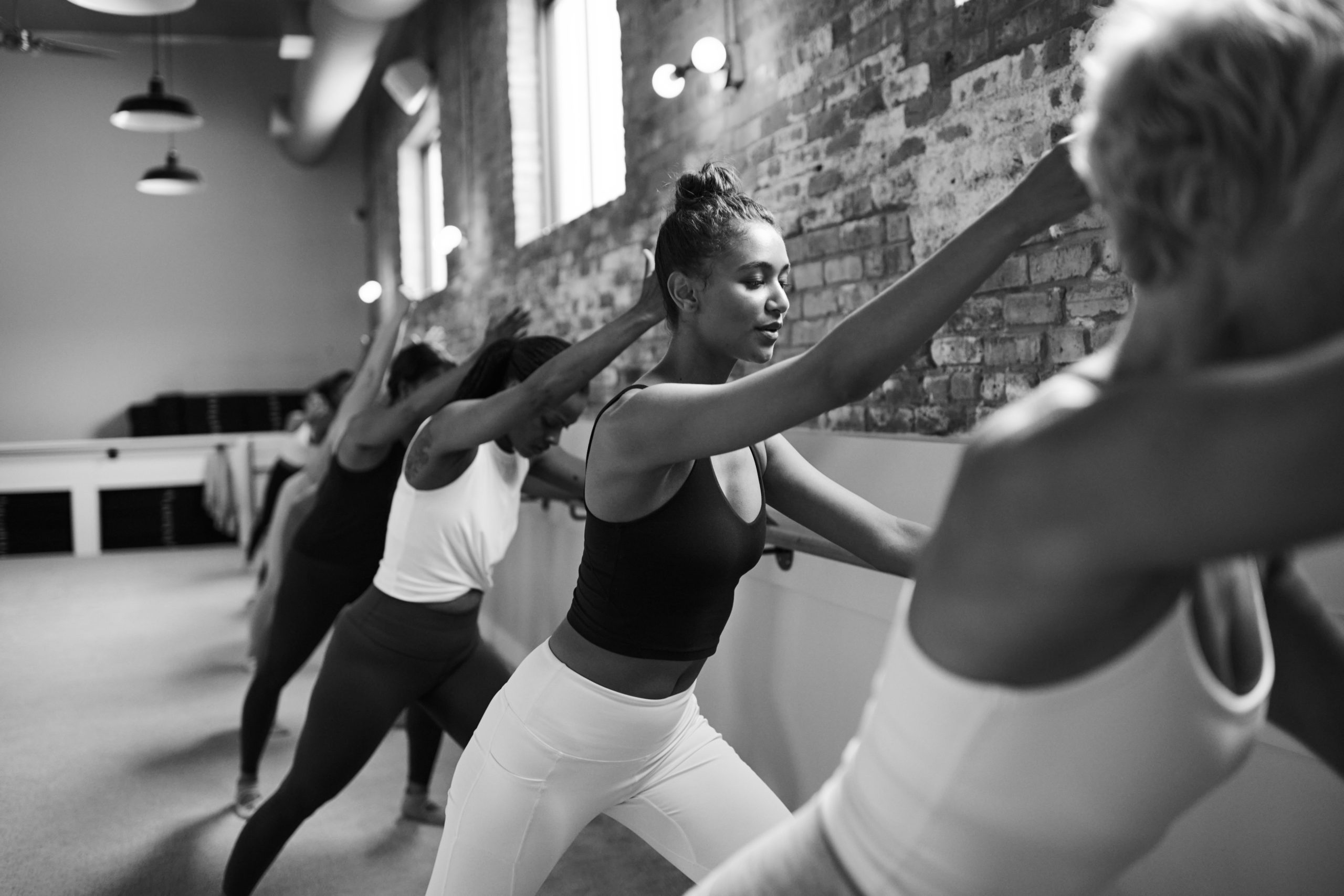 Black and white image of women practicing tilted seat at the barre in Bar Method studio