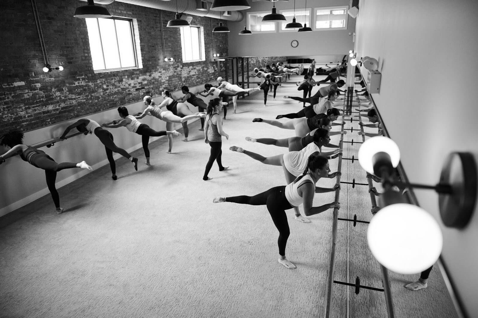 Black and white image of a group of people on a barre cardio class